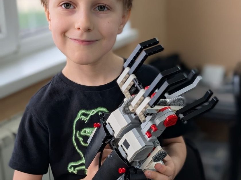 Мальчик держит робота-манипулятора, собранного на Mindstorms, в ТЕХНОклубе Омск